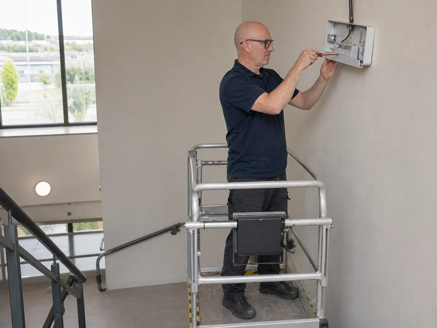 MCI Electrical electrician installing an emergency light in a commercial stairwell by MCI Electrical
